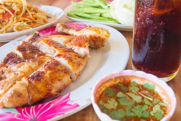 Refeição picante de estilo tailandês, frango grelhado com salada de papaia picante e bebida gelada