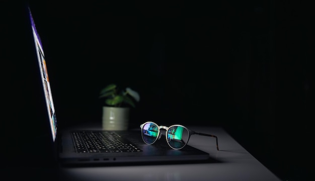 Reflexão de um laptop em óculos em um fundo escuro