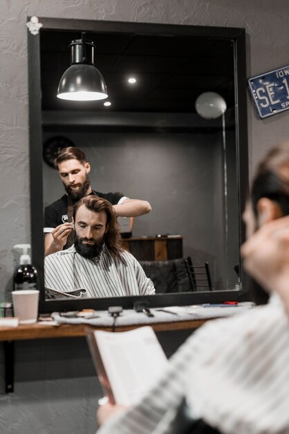 Reflexão do cabelo de um homem de corte de barbeiro no espelho