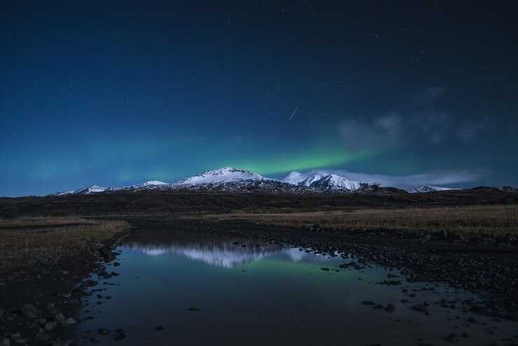 Reflexo de uma montanha coberta de neve no rio durante a noite