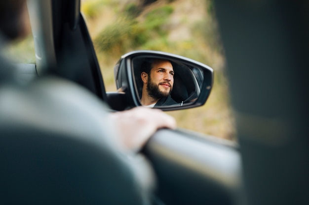 Reflexo do macho feliz no espelho lateral do carro
