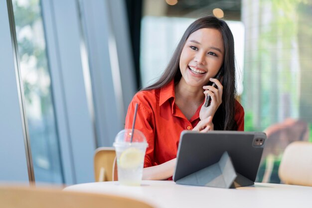 Relaxe o sorriso do empreendedor freelance feminino asiático inteligente atraente de lazer e divirta-se trabalhando com smartphone e laptop no café com conceito de ideias casuais de nômade digital de negócios de cidade borrada