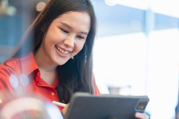 Relaxe o sorriso do empreendedor freelance feminino asiático inteligente atraente de lazer e divirta-se trabalhando com smartphone e laptop no café com conceito de ideias casuais de nômade digital de negócios de cidade borrada