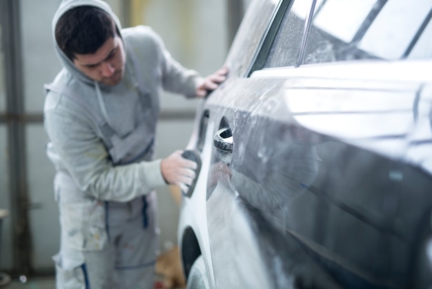 Reparador preparando carro para pintura na oficina