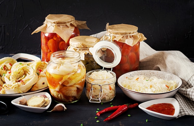 Repolho kimchi, tomate marinado, frascos de vidro azedo chucrute sobre a mesa da cozinha rústica.