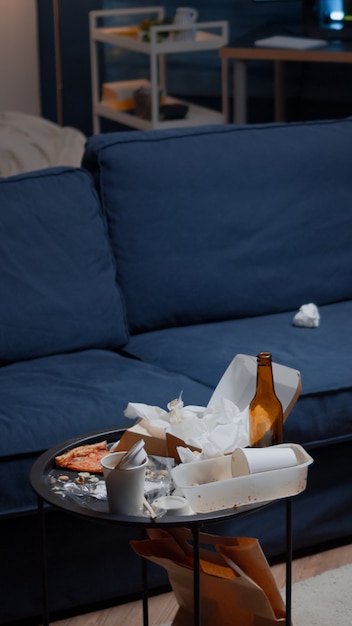 Foto grátis restos de pizza, garrafas de cerveja vazias e guardanapos na mesa da sala de estar bagunçada