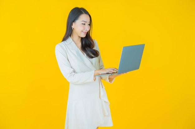 Retrate o sorriso da bela jovem asiática com computador portátil em fundo isolado