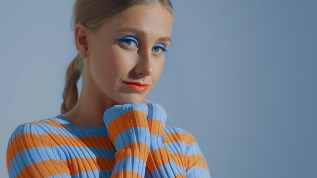 Retrato aproximado de uma jovem modelo com maquiagem colorida com as mãos tocando seu queixo