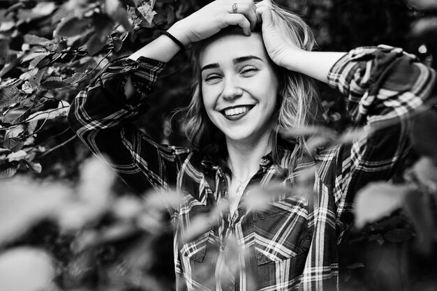 Retrato aproximado de uma loira sorridente em camisa tartan no campo