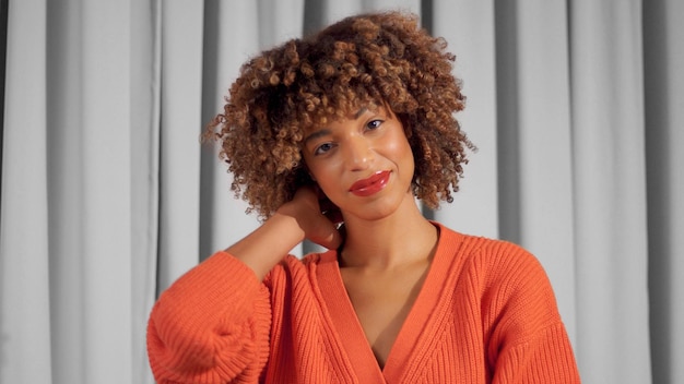 Retrato aproximado de uma mulher negra de raça mista sorridente com cabelo encaracolado texturizado com maquiagem natural para tons de pele escuros