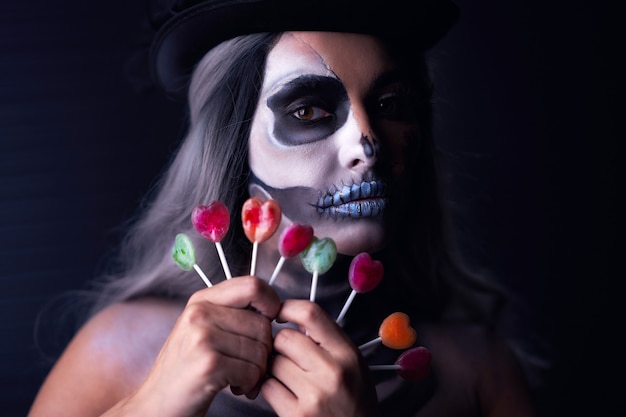 Retrato assustador de mulher com maquiagem gótica de halloween segurando pirulitos