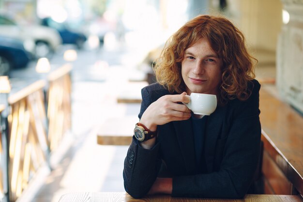 Retrato avermelhado na moda homem bebendo café