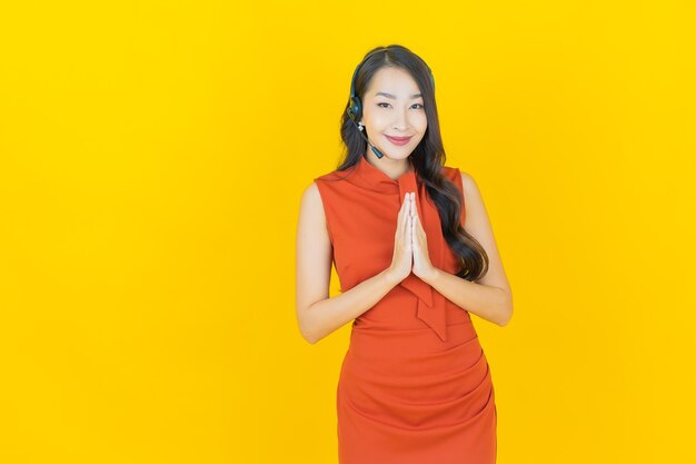 Retrato bela jovem asiática com centro de atendimento ao cliente call center em amarelo