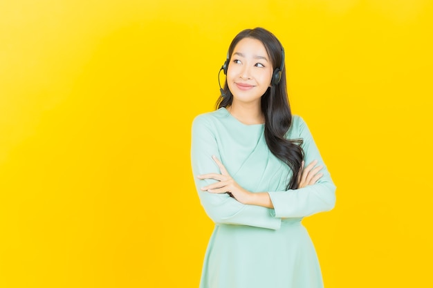 Retrato bela jovem asiática com centro de atendimento ao cliente de call center em amarelo