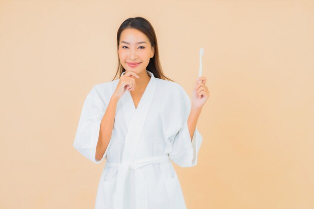 Retrato bela jovem asiática com escova de dentes em bege