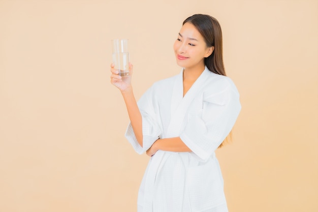 Retrato bela jovem asiática com garrafa de água para bebida em bege
