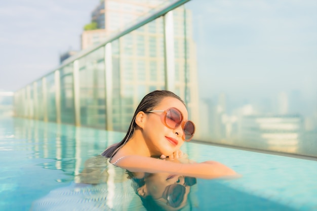 Retrato bela jovem asiática relaxando lazer ao redor da piscina em hotel resort para viagens de férias