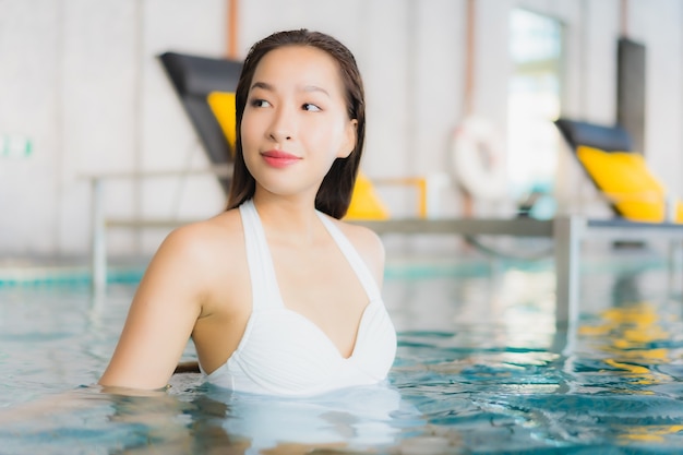 Retrato bela jovem asiática relaxando sorriso ao redor da piscina em hotel resort em traval férias