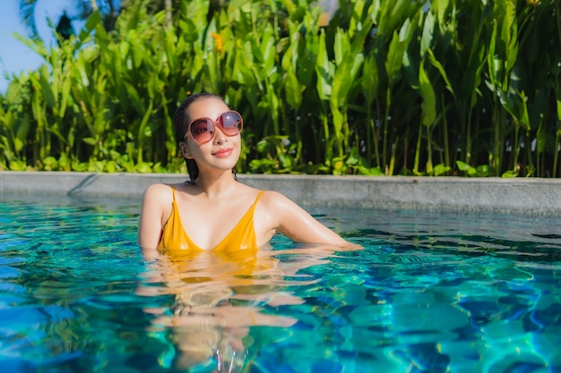 Retrato bela jovem asiática relaxando sorriso feliz ao redor da piscina em hotel resort para férias de lazer