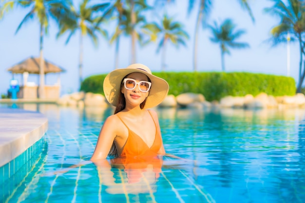 Retrato bela jovem asiática relaxando sorriso lazer ao redor da piscina ao ar livre com vista para o mar