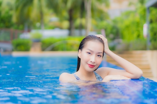 Retrato bela jovem asiática relaxando sorriso lazer ao redor da piscina em hotel resort em viagem de férias