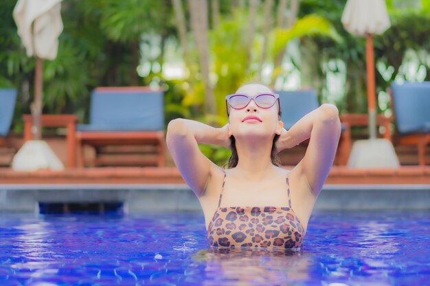 Retrato bela jovem asiática relaxando sorriso lazer ao redor da piscina em viagens de férias de férias