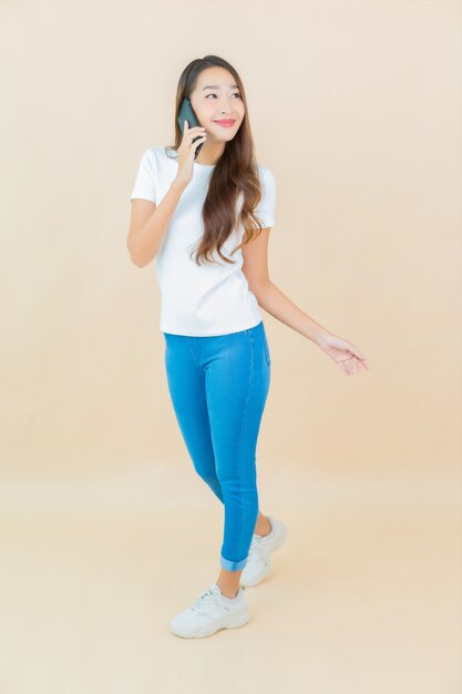 Retrato bela jovem asiática usando telefone celular inteligente bege