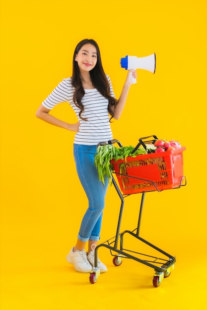 Retrato bela jovem mulher asiática com carrinho de compras e megafone