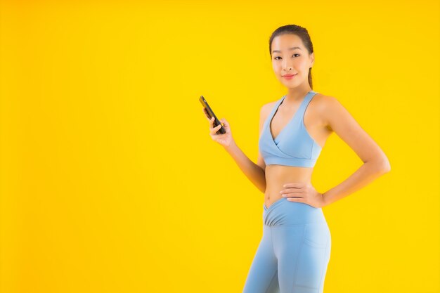 Retrato bela jovem mulher asiática com telefone móvel esperto amarelo isolado