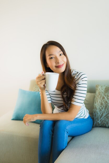 Retrato bela jovem mulher asiática no sofá com uma xícara de café