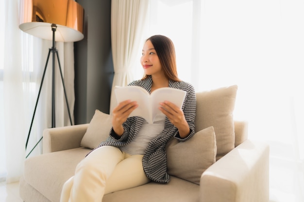 Retrato belas jovens mulheres asiáticas lendo livro e sentado na cadeira do sofá