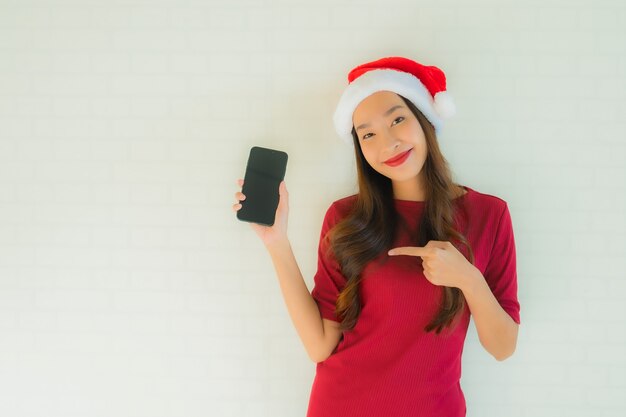 Retrato belas jovens mulheres asiáticas usam chapéu de Natal santa com telefone móvel