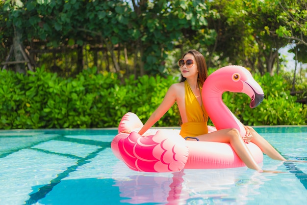 Retrato, bonito, jovem, mulher asian, ligado, a, flamingo, flutuador inflável, em, piscina, em, hotel, recurso