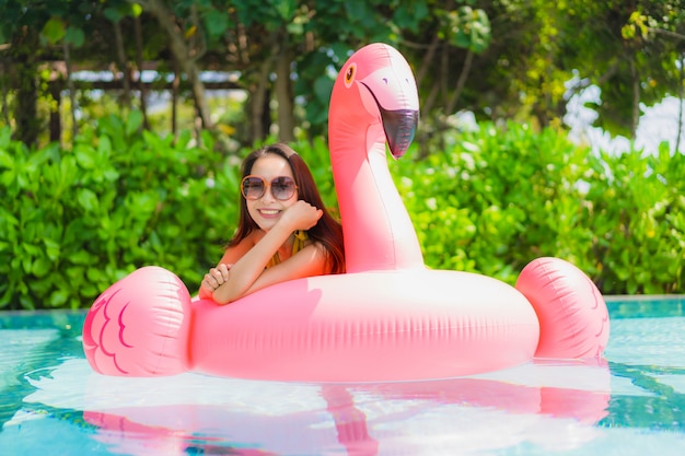 Retrato, bonito, jovem, mulher asian, ligado, a, flamingo, flutuador inflável, em, piscina, em, hotel, recurso