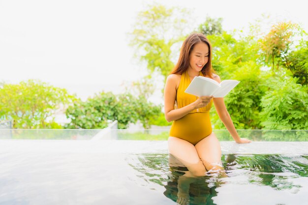 Retrato, bonito, jovem, mulher asian, livro leitura, em, piscina, em, hotel, e, recurso