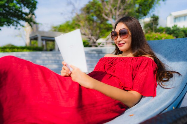 Retrato, bonito, jovem, mulher asian, livro leitura, em, piscina, em, hotel, e, recurso