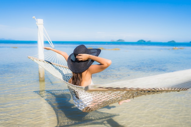 Foto grátis retrato, bonito, jovem, mulher asian, sentando, ligado, rede, ao redor, mar, praia, oceânicos, para, relaxe