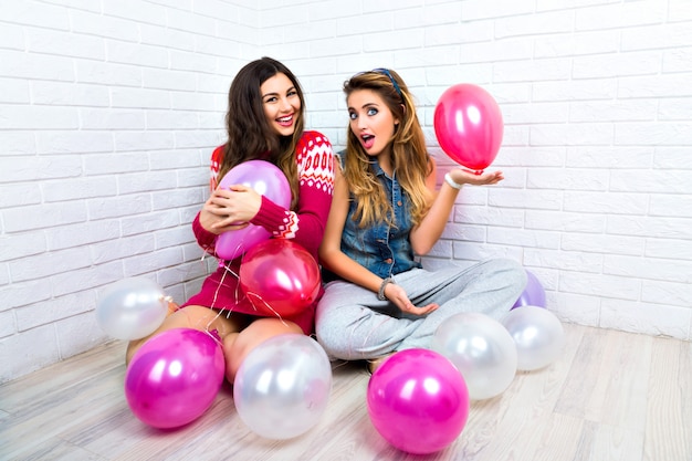 Retrato brilhante interno de duas apostas engraçadas amigos irmã hipster mulher, enlouquecendo, hora da festa, balão rosa, mostrando v ciência, abraços e beijos, maquiagem, blusas, sorriso incrível.