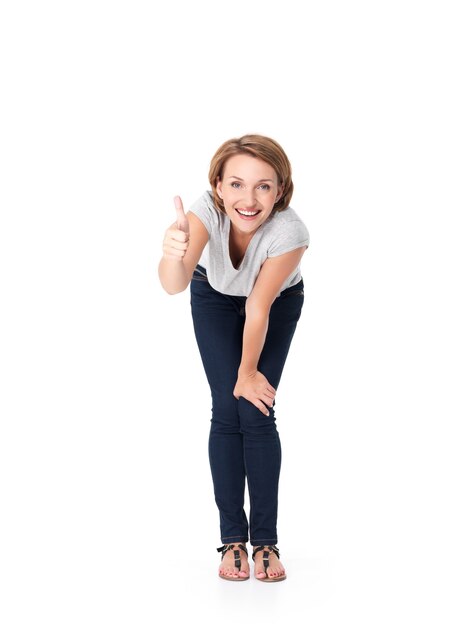 Retrato completo da bela mulher feliz em pé e mostrando o gesto de polegar para cima em branco