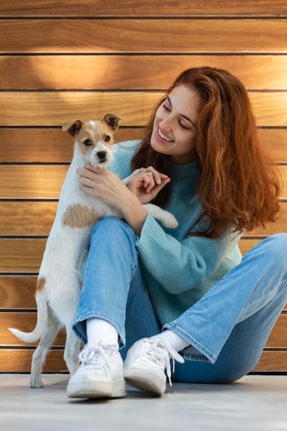 Retrato completo de mulher posando com um cachorro fofo