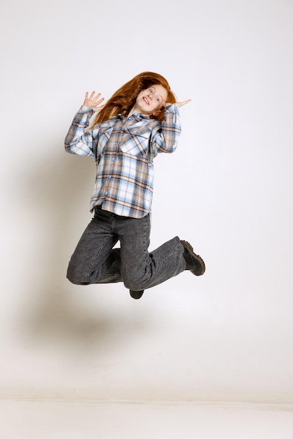 Retrato completo de uma jovem em pano casual pulando posando isolado sobre o fundo branco do estúdio Foto Premium