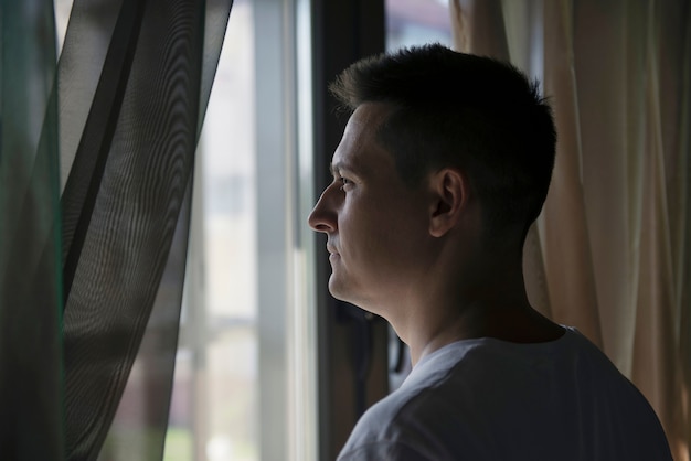 Retrato criativo do homem com cortinas e sombras da janela