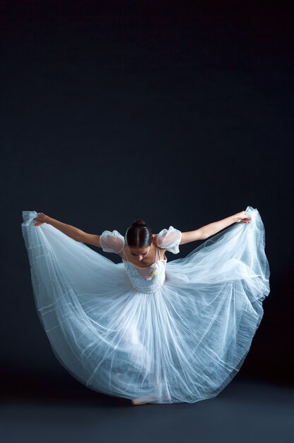 Retrato da bailarina clássica em vestido branco na superfície preta