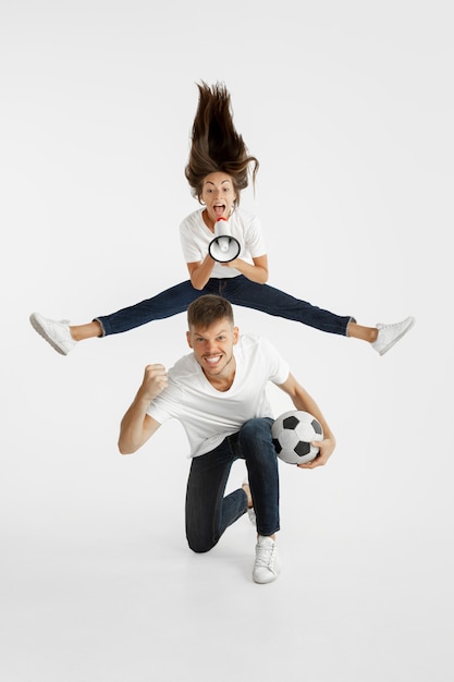 Retrato da bela jovem casal futebol ou fãs de futebol. expressão facial, emoções humanas, publicidade, conceito de esporte. mulher e homem pulando, gritando, se divertindo.