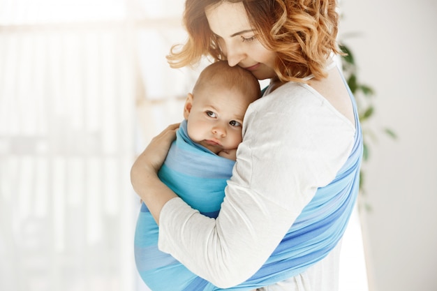 Retrato da bela jovem mãe segurando firme seu bebê recém-nascido com amor e carinho. ela sorrindo e sentindo a felicidade dos momentos de maternidade.