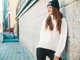 Foto grátis retrato da bela modelo sorridente. mulher vestida com um gorro e uma camisola branca hippie quente. posando na rua