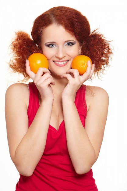 Foto grátis retrato da bela ruiva sorridente mulher ruiva no pano vermelho isolado no branco com laranjas