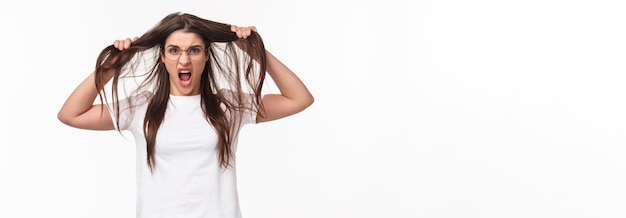 Retrato da cintura para cima de uma jovem namorada chateada e irritada irritada perdendo a paciência puxando o cabelo