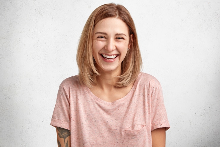 Foto grátis retrato da cintura para cima de uma linda jovem satisfeita com um penteado estiloso, sorri ampla e alegremente para a câmera e está animado como no fim de semana