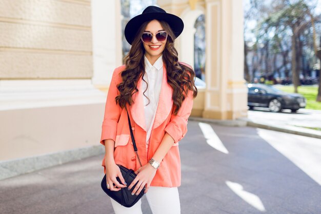 Retrato da moda da mulher elegante com roupa casual, andando na cidade.